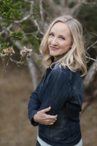 Karen Zachary, owner of Anchor Virtual Assistants, wearing a dark denim coat, standing in front of a tree.