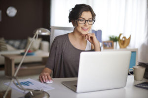 brunette woman working at laptop on a white desk