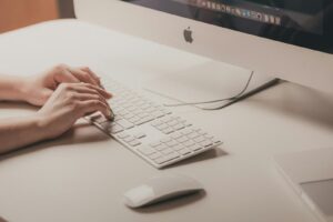 Close-up of hands typing on an Apple keyboard